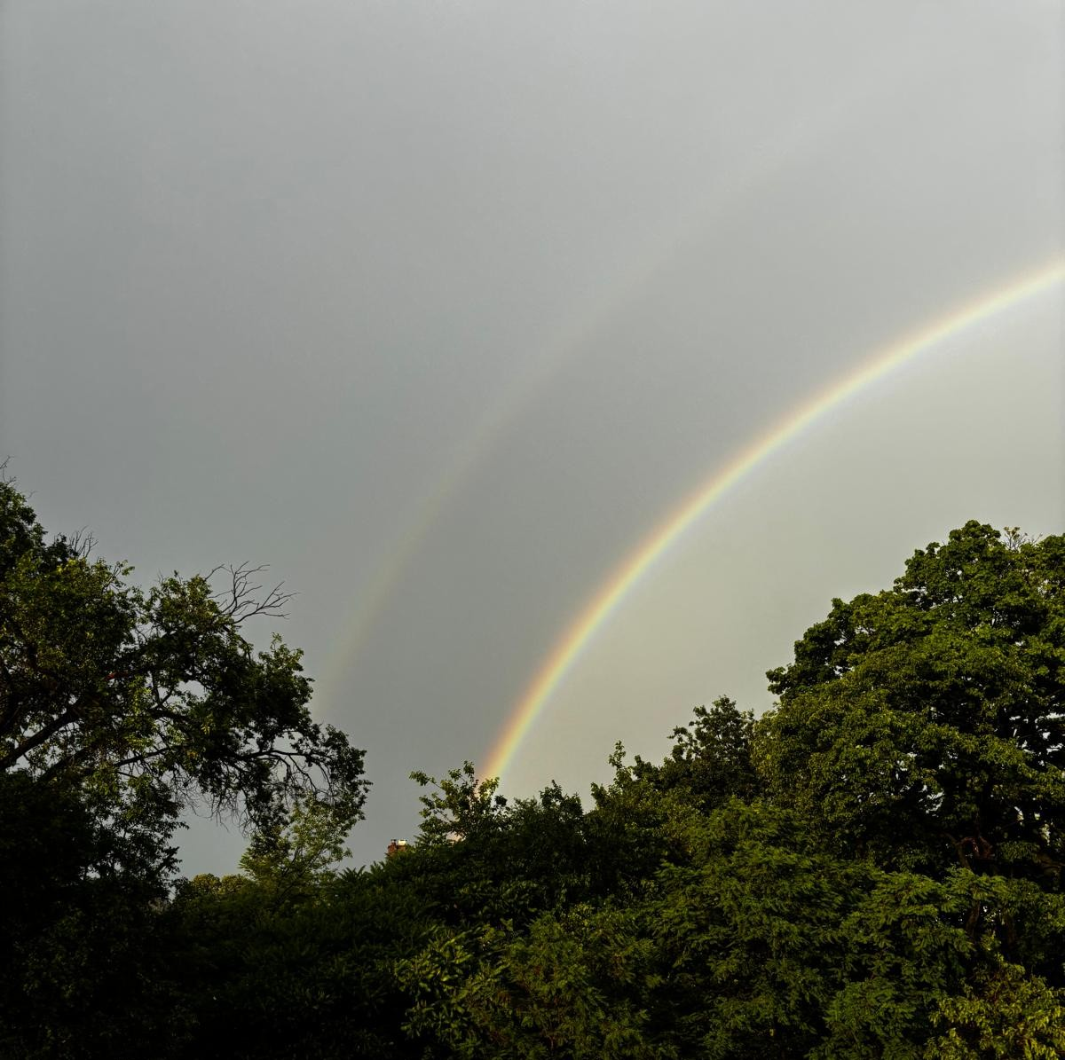 photo of the sky taken out of a car window of a double rainbow, one is more faded than the other